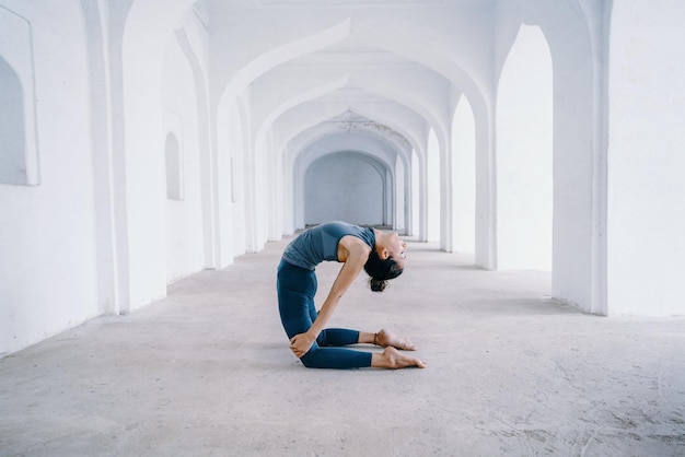 Jovem fêmea fazendo pose de asana em um antigo templo indiano