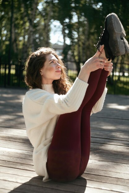 Foto jovem fêmea praticando ioga navasana pose ao ar livre