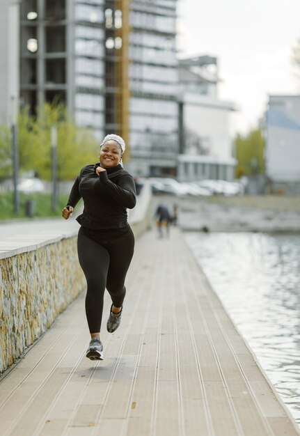 Jovem fêmea se divertindo treinando ao ar livre. Conceito de estilo de vida de pessoas desportivas. Mulher em roupas esportivas correndo