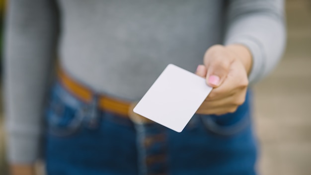 Foto jovem fêmea segurando o cartão de crédito em branco, ao ar livre