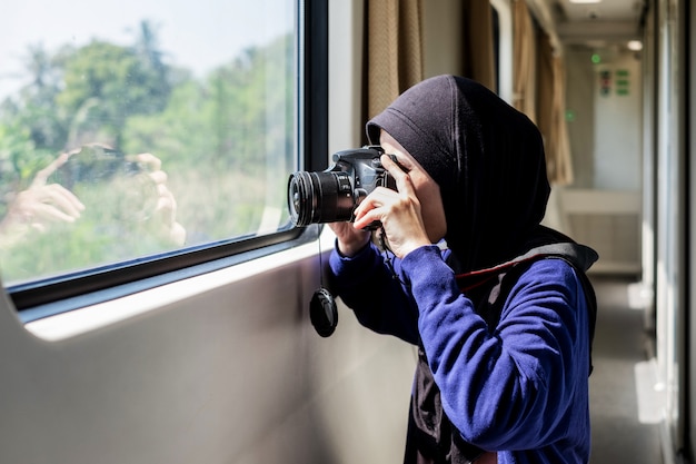 Jovem fêmea vestindo o hijab tirando uma foto de dentro de um trem.