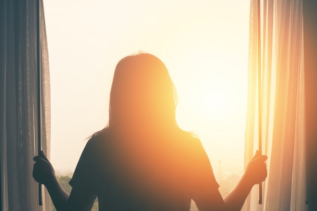 Foto jovem fica no quarto cortina aberta veja o nascer do sol depois de acordar