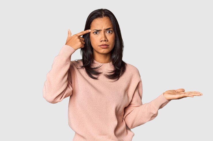 Foto jovem filipina com longos cabelos pretos em estúdio segurando e mostrando um produto na mão