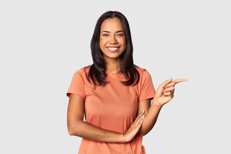 Foto jovem filipina com longos cabelos pretos no estúdio sorrindo alegremente apontando com o dedo indicador