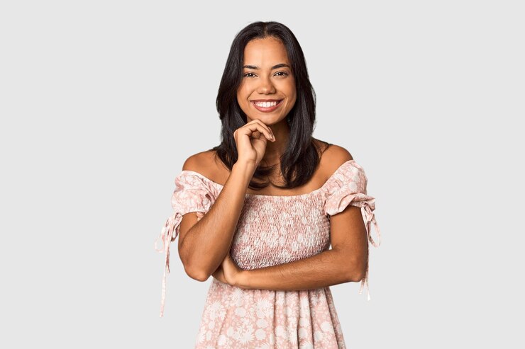 Foto jovem filipina com longos cabelos pretos no estúdio sorrindo feliz e confiante tocando o queixo com a mão