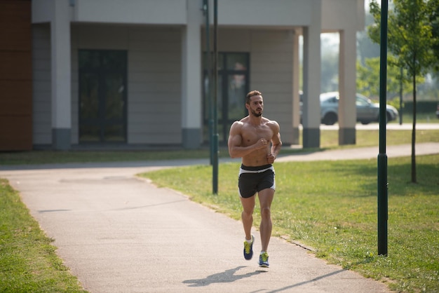 Jovem fisiculturista correndo na área do parque treinando e exercitando para Trail Run Maratona Endurance Fitness Conceito de estilo de vida saudável