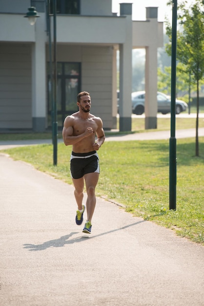 Jovem fisiculturista correndo na área do parque treinando e exercitando para Trail Run Maratona Endurance Fitness Conceito de estilo de vida saudável