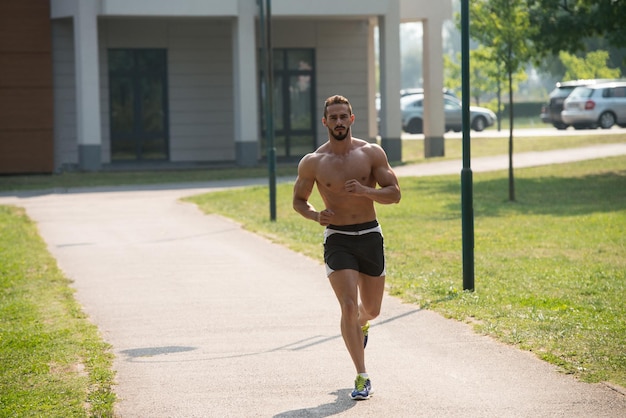 Jovem fisiculturista correndo na área do parque treinando e exercitando para Trail Run Maratona Endurance Fitness Conceito de estilo de vida saudável