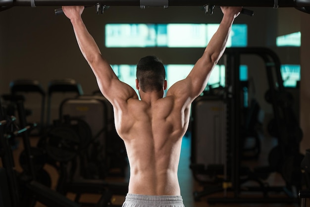 Jovem fisiculturista masculino fazendo exercícios de peso pesado para as costas