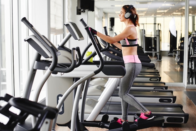 Jovem fitness fazendo exercícios na máquina na academia