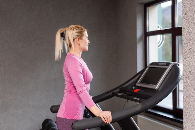 Jovem fitness mulher executa exercícios com máquina de exercícios na academia, foto horizontal