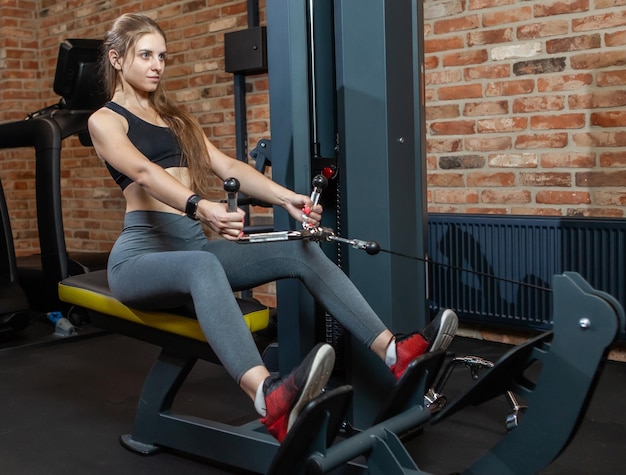 Jovem fitness pratica exercícios para as costas com a máquina de exercícios Cable Crossover em uma academia moderna