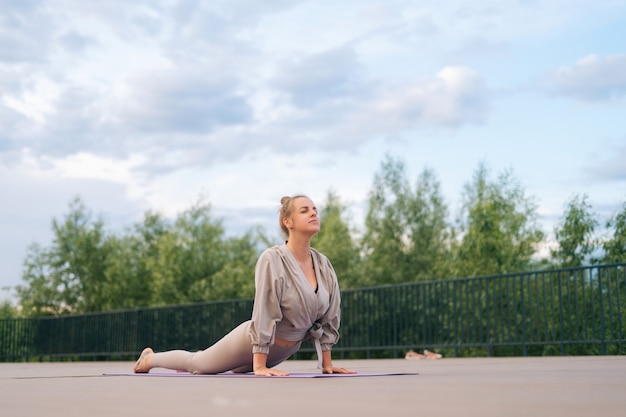 Jovem flexível com corpo esportivo fazendo exercícios de ioga para cima, roda para cima ou pose de arco deitada na esteira de ioga
