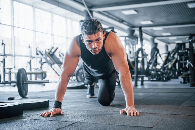 Jovem forte em roupas esportivas fazendo flexões no ginásio