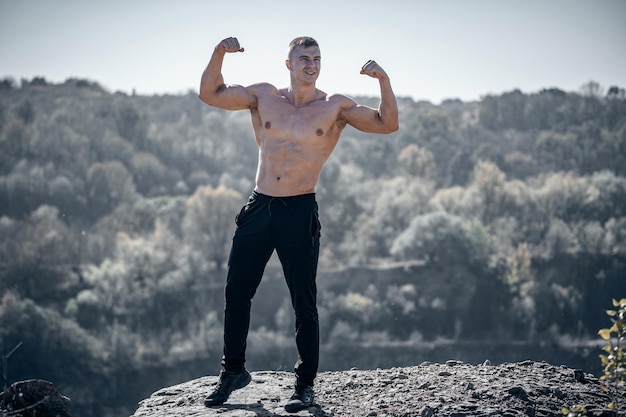 Jovem forte sem camisa ao ar livre posando Macho musculoso em topless masculino