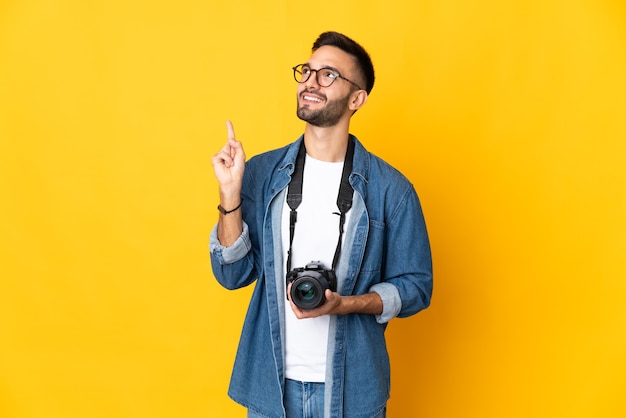 Jovem fotógrafa isolada em um fundo amarelo apontando uma ótima ideia