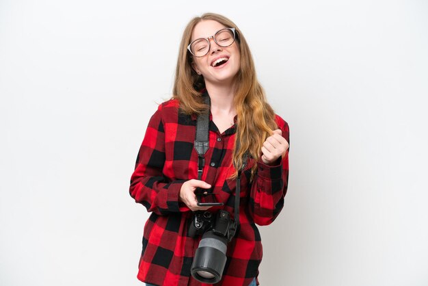 Jovem fotógrafa linda mulher isolada no fundo branco com telefone em posição de vitória