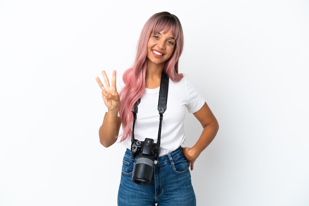 Jovem fotógrafa mulher de raça mista com cabelo rosa isolado no fundo branco feliz e contando três com os dedos