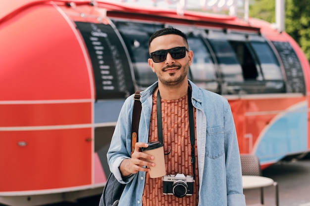 Jovem fotógrafo com bebida e fotocâmera