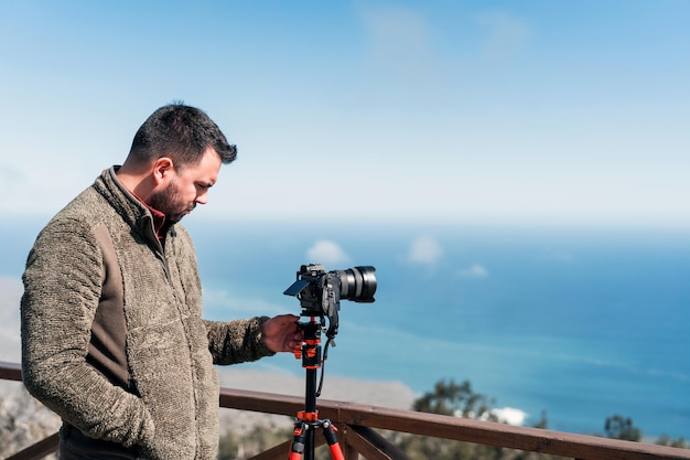 Jovem fotógrafo de pé no mirante tirando fotos da paisagem sobre o oceano pacífico x9