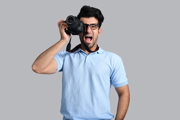 jovem fotógrafo gritando e segurando a câmera modelo paquistanês indiano