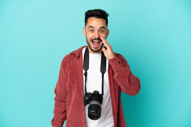 Jovem fotógrafo homem caucasiano isolado em um fundo azul com expressão facial de surpresa e choque