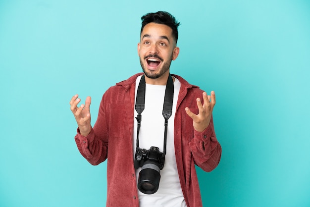 Jovem fotógrafo homem caucasiano isolado em um fundo azul com expressão facial surpresa