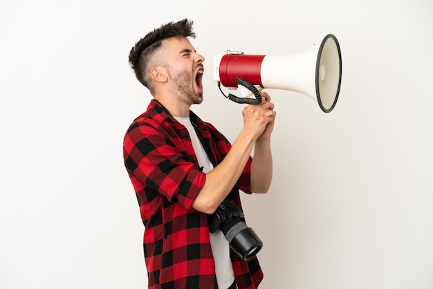 Foto jovem fotógrafo homem caucasiano isolado no fundo branco gritando através de um megafone