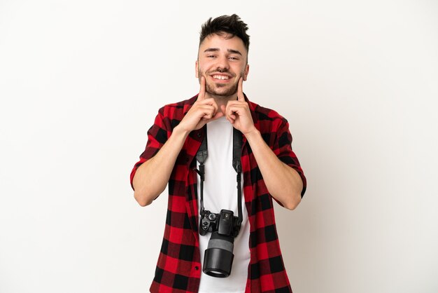 Jovem fotógrafo homem caucasiano isolado no fundo branco sorrindo com uma expressão feliz e agradável