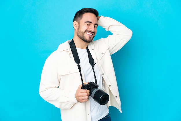 Jovem fotógrafo isolado em um fundo azul sorrindo muito