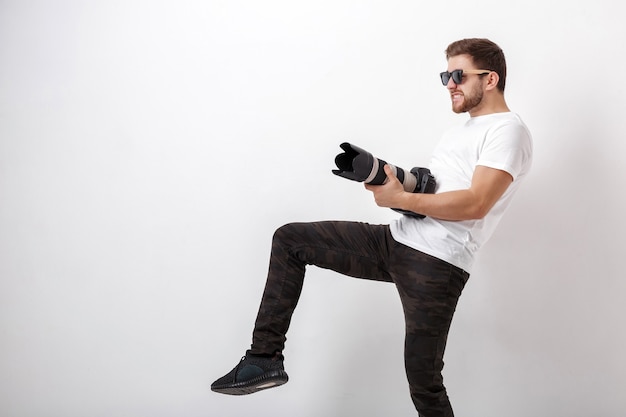 Jovem fotógrafo profissional em uma camisa branca pronto para a fotografia e usando uma câmera digital com uma lente longa