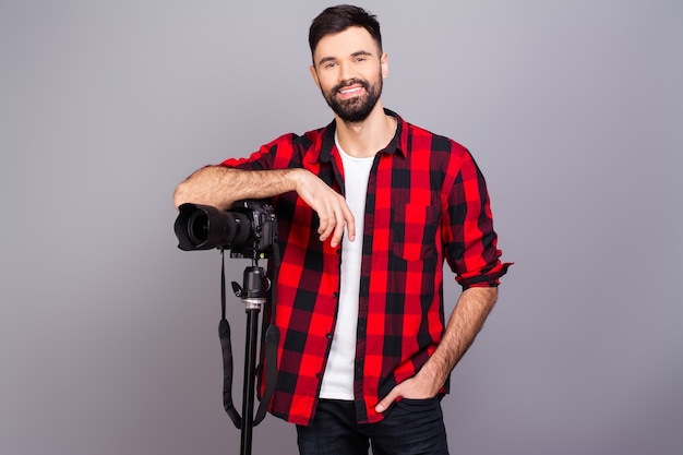 Jovem fotógrafo sorridente de camisa vermelha e câmera profissional