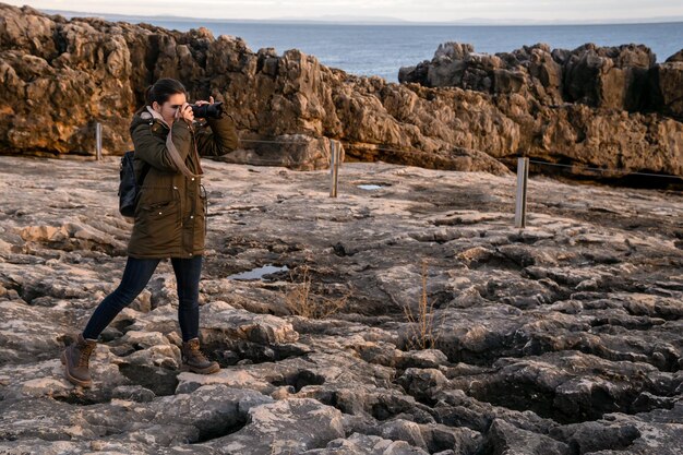 Jovem fotógrafo tirando fotos com sua câmera na natureza