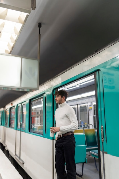 Jovem francês andando de metrô e tomando café