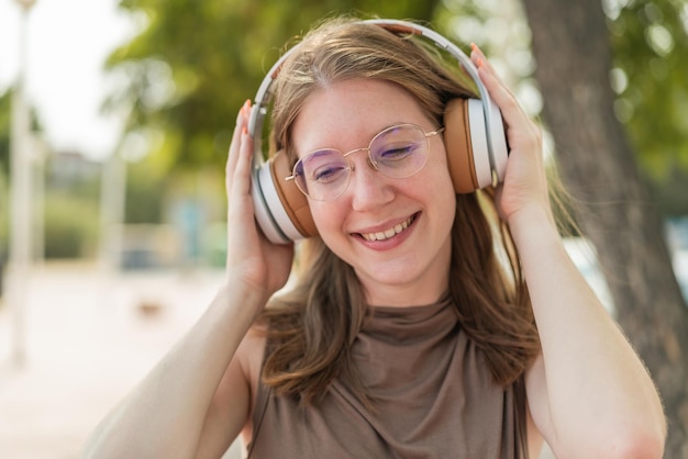 Foto jovem francesa com óculos ao ar livre ouvindo música