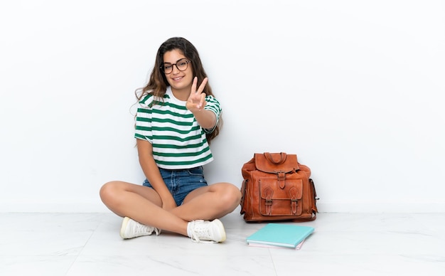 Foto jovem francesa isolada em fundo azul com chapéu de inverno tendo dúvidas ao olhar para cima