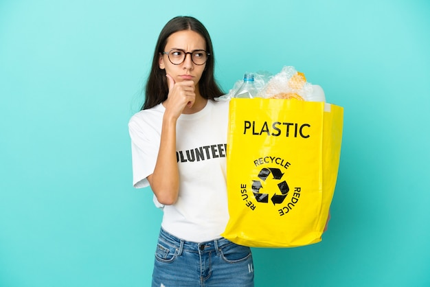 Jovem francesa segurando uma sacola cheia de garrafas plásticas para reciclar, tendo dúvidas