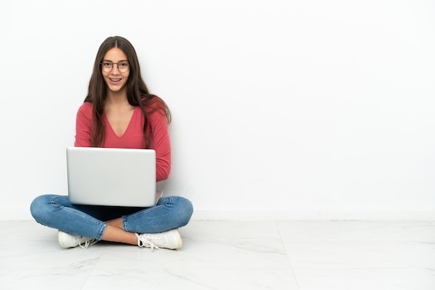 Jovem francesa sentada no chão com seu laptop com os braços cruzados e olhando para a frente