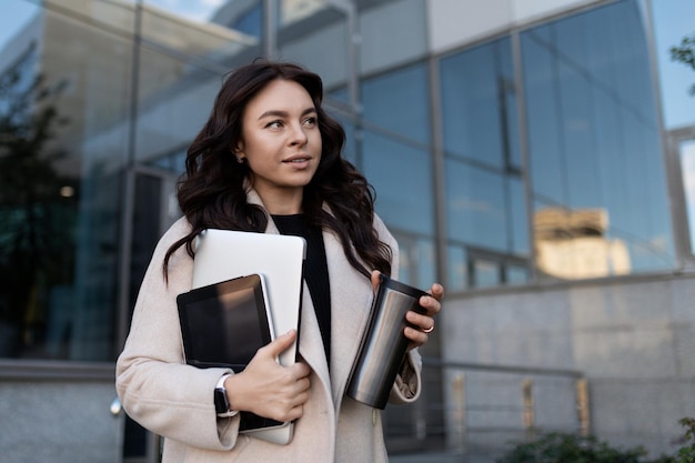 Jovem freelancer com uma caneca e um tablet nas mãos na rua