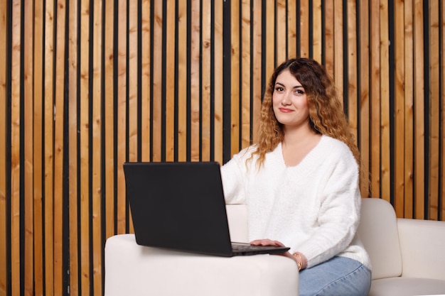 Jovem freelancer está em casa no sofá, usando um laptop