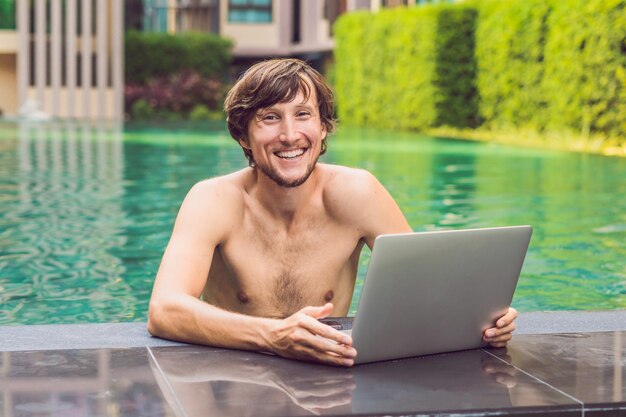 Jovem freelancer trabalhando de férias à beira da piscina.