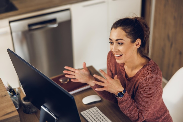 Foto jovem freelancer usando um computador para fazer uma videochamada enquanto trabalha em seu escritório em casa.