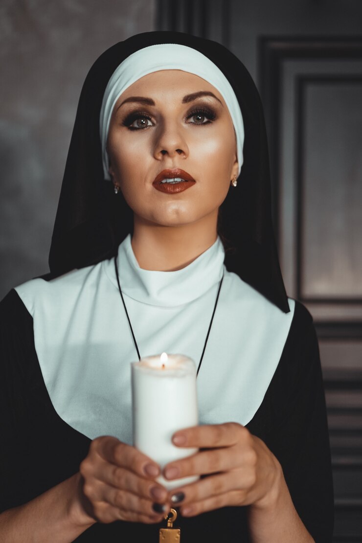 Foto jovem freira católica está segurando uma vela nas mãos. foto em fundo preto. retrato de mulher bonita