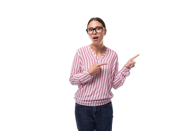 Foto jovem funcionária de escritório alegre vestida com uma camisa rosa-branca aponta para um espaço vazio