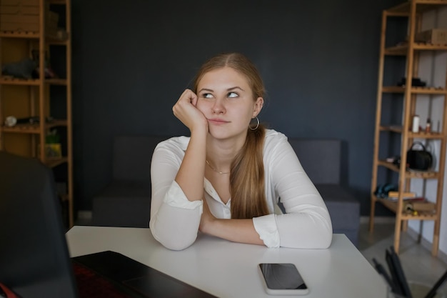 Jovem funcionário de sucesso, mulher de negócios com camisa branca cansada sentada na mesa branca no local de trabalho