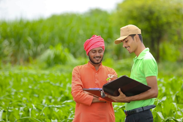 Jovem funcionário do banco na Índia, concluindo a papelada com os agricultores no campo de agricultura.