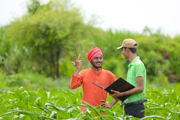 Jovem funcionário do banco na Índia, concluindo a papelada com os agricultores no campo de agricultura.