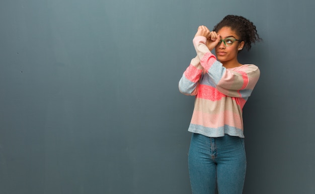 Jovem garota afro-americana de olhos azuis, fazendo o gesto de uma luneta