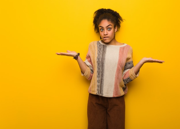 Foto jovem garota afro-americana negra com olhos azuis confusos e duvidosos