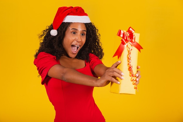 Jovem garota afro segurando um expressivo presente de Natal.